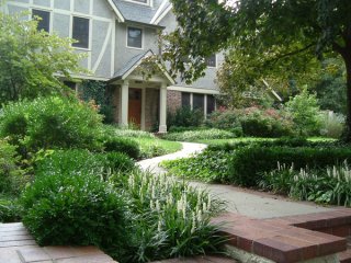 A curving front walk and layers of plants extend the traditional foundation-planting scheme out to the edge of the property. It's much more interesting than a line of shrubs in front of the house.