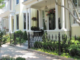 Boxwoods are the most prominent plant in this tiny front yard. The combination of upright species and low, trimmed plantings look very crisp, but welcoming. The porch, with plants in pots and hanging baskets, brings the garden all the way up to the front door.