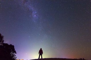 Dylan O'Donnell standing on rock in front of sky full of stars.