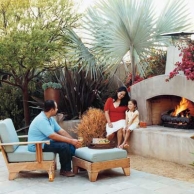 family enjoying outdoor living space with fireplace and lounge chair