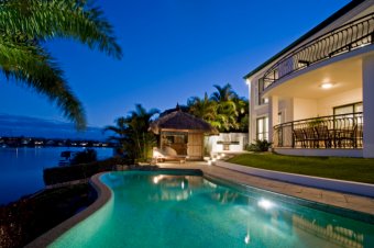 Waterfront pool at night in backyard of luxury Mediterranean style home